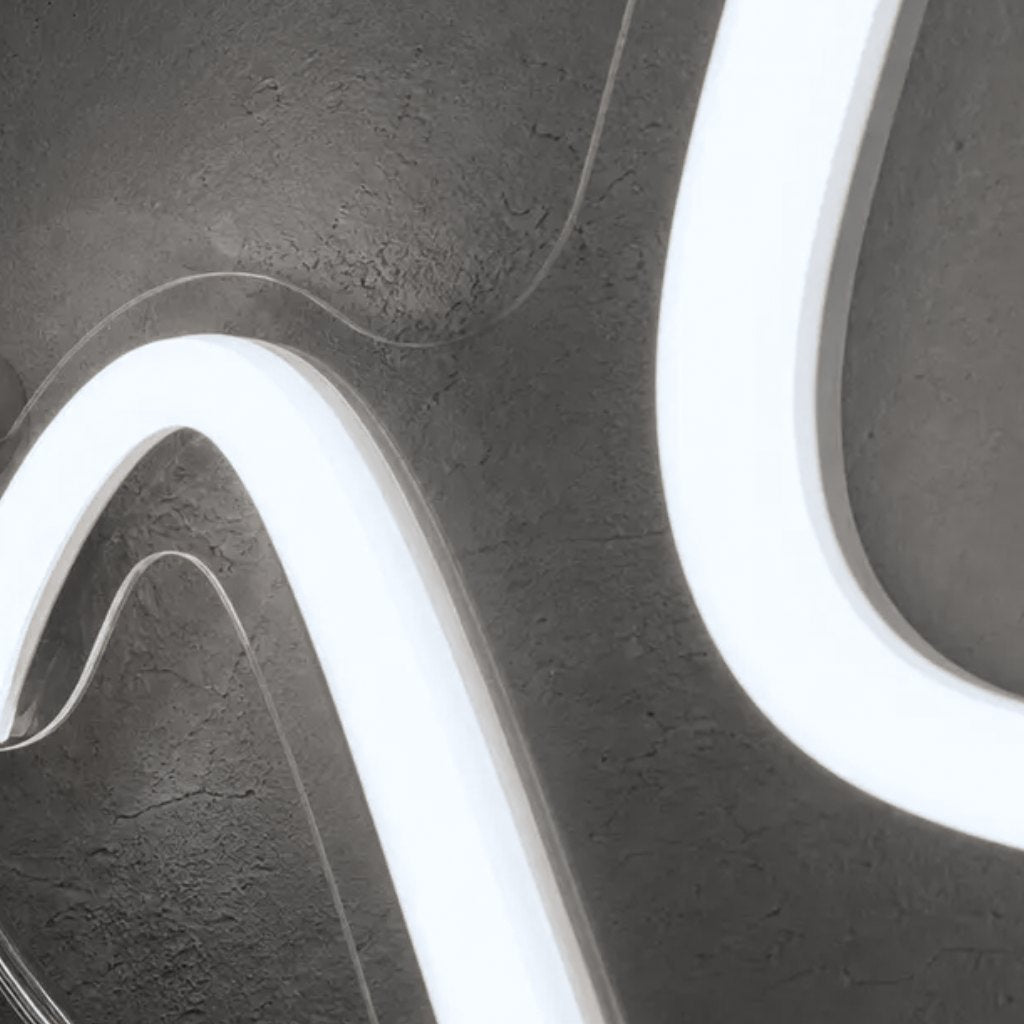 Close-up of clear acrylic cut closely around curving cool white neon LED tubes on a textured grey wall, V360 Photobooths